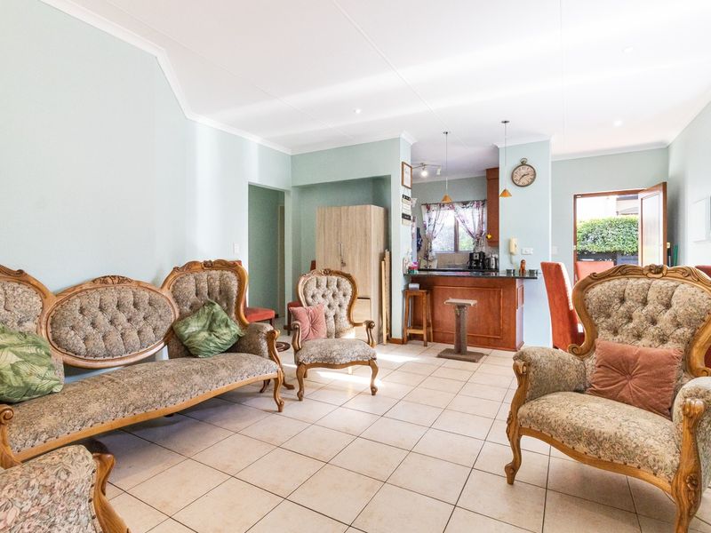 An open-plan living and kitchen area featuring tiled flooring, a breakfast bar, and neutral wall finishes, providing a functional and connected living space.