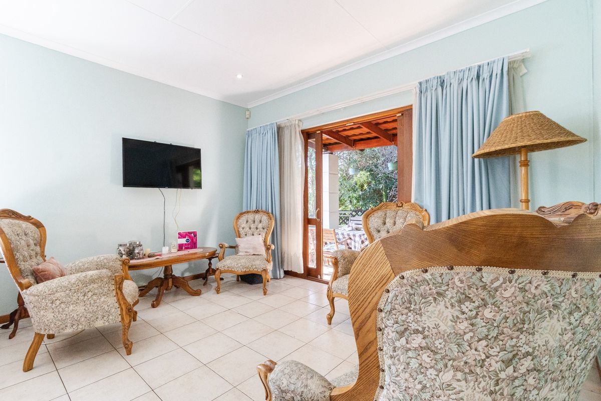 A bright living room featuring tiled flooring, coved ceilings, and a sliding glass door providing direct access to an outdoor patio area.