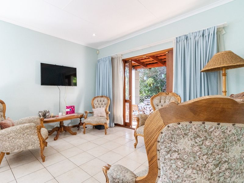 A bright living room featuring tiled flooring, coved ceilings, and a sliding glass door providing direct access to an outdoor patio area.