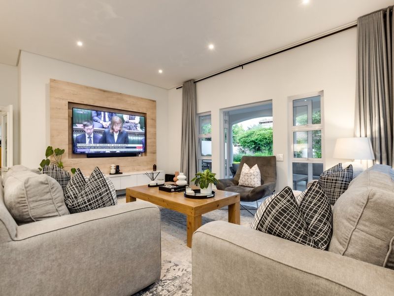 A well-appointed living room featuring a timber accent wall, recessed lighting, and large aluminium-framed doors providing seamless access to the outdoor patio area.