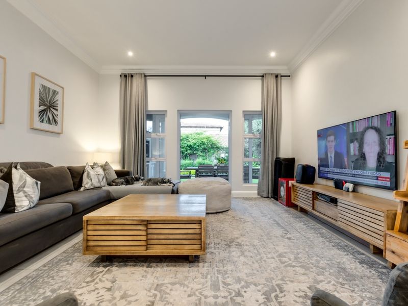 Spacious living room featuring tiled flooring, recessed downlighting, and large sliding glass doors providing direct access to the rear patio and garden.