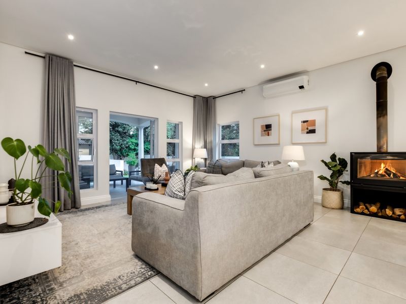 A bright and modern living room featuring large format floor tiles, a built-in fireplace, and direct access to an outdoor patio area.