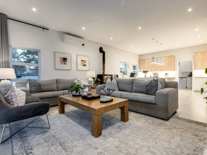 A modern open-plan living and kitchen area featuring tiled floors, a fireplace, split-system air conditioning, and contemporary cabinetry with integrated lighting.