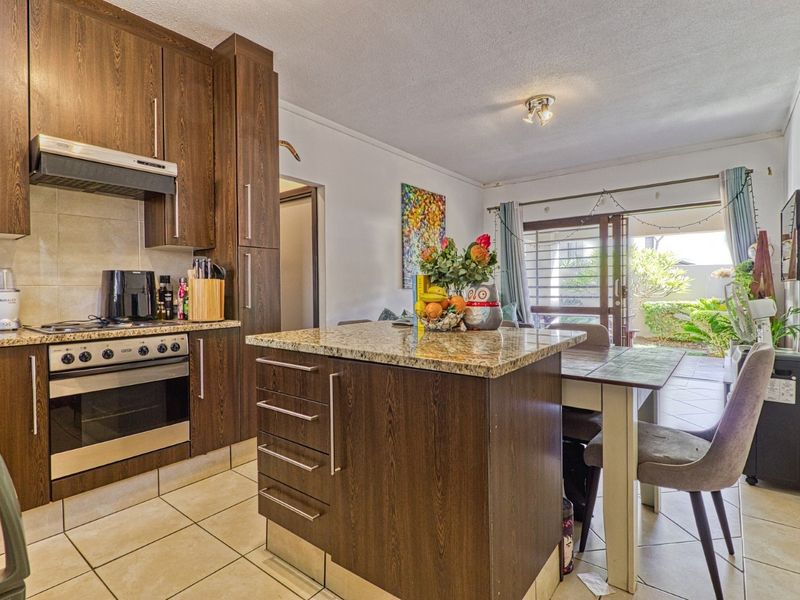 Open-plan kitchen and dining area featuring dark wood cabinetry, granite countertops, built-in oven, and direct access to an outdoor patio through sliding glass doors.