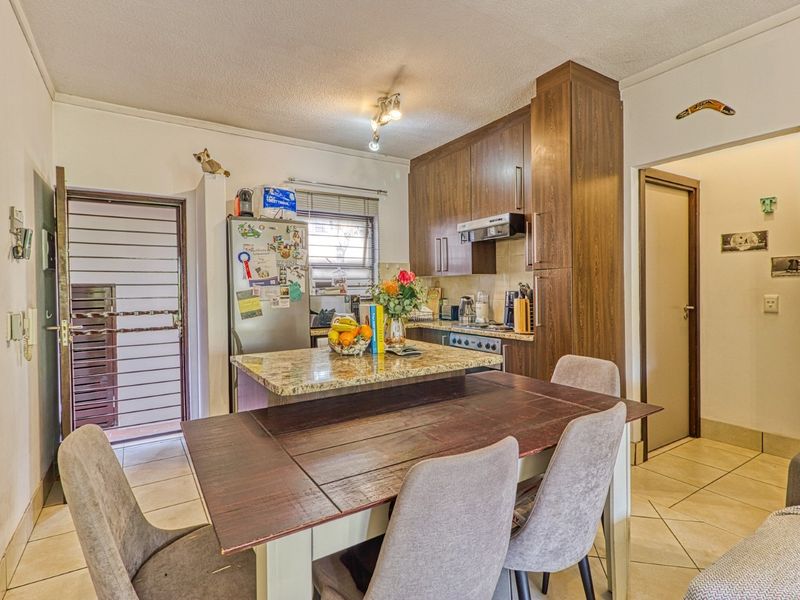 Open-plan kitchen and dining area featuring granite countertops, wood-finish cabinetry, and tiled flooring, providing a functional space for cooking and casual dining.