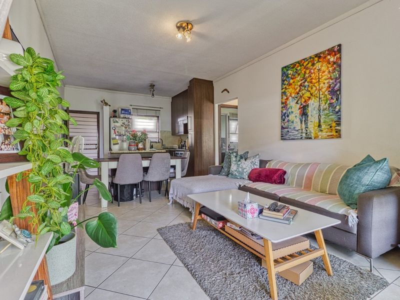 Open-plan living and kitchen area featuring tiled flooring and functional built-in cabinetry, providing a versatile space for daily living and dining.