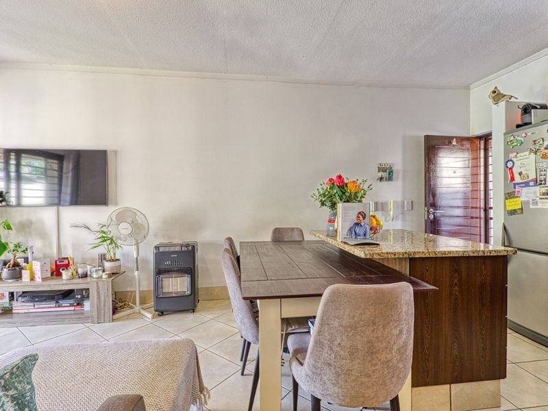 Open-plan living and dining area featuring tiled flooring and a kitchen island with granite countertops, providing a functional and connected living space.