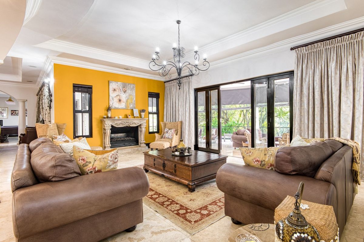 Spacious living room featuring a stone fireplace, elegant tray ceiling with crown molding, and large sliding glass doors opening to an outdoor patio area.