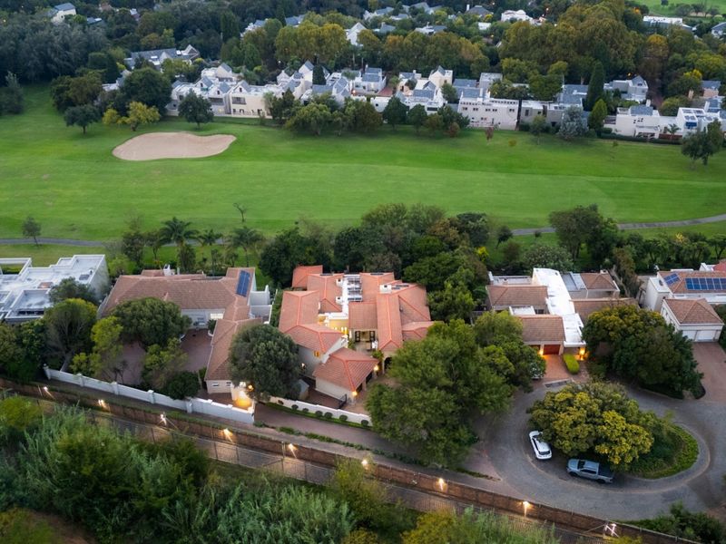 Aerial view of a residential property featuring a tiled roof, solar panels, and a paved driveway, situated adjacent to a golf course.