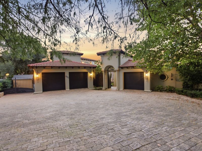 A well-maintained front elevation featuring a triple garage, paved driveway, and an inviting arched entrance under a classic terracotta tiled roof.