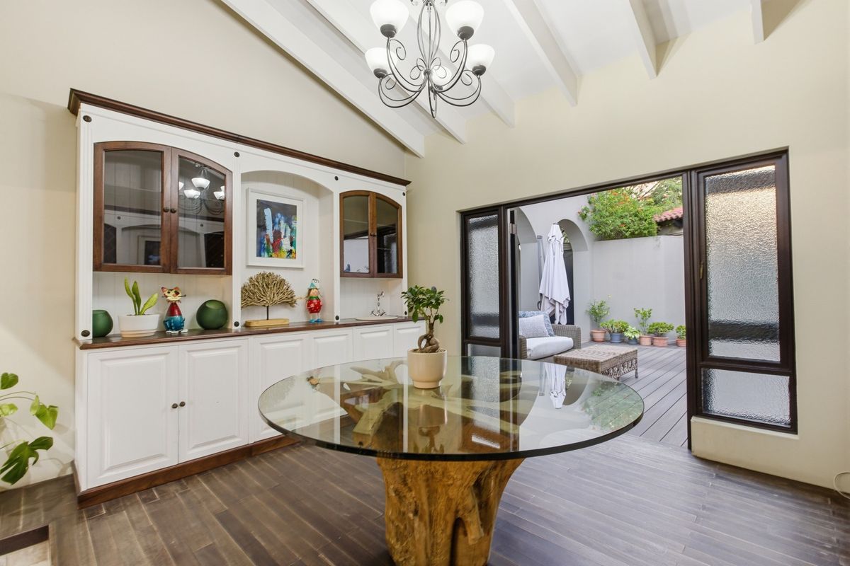 A bright living area featuring custom built-in cabinetry, exposed ceiling beams, and seamless access to an outdoor patio through large sliding glass doors.