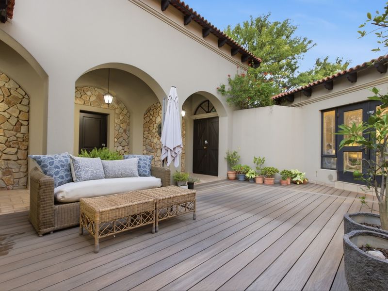 A well-maintained covered patio area featuring timber decking, stone-clad walls, and elegant arched architectural details, providing a seamless transition to the outdoor space.