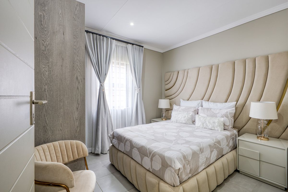 A well-maintained bedroom featuring tiled flooring, recessed ceiling lighting, and a large built-in cupboard with a modern wood-grain finish.