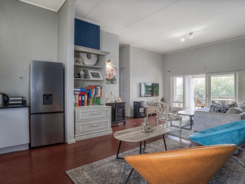 An open-plan living and kitchen area featuring laminate flooring, built-in cabinetry, and large sliding glass doors leading to an outdoor space.