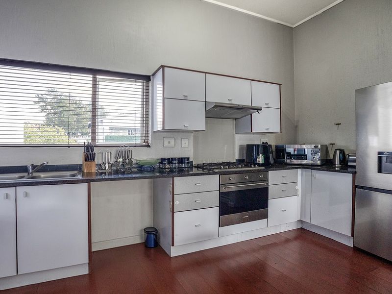 A functional kitchen featuring white cabinetry, dark laminate countertops, a gas hob with extractor fan, and integrated stainless steel oven.