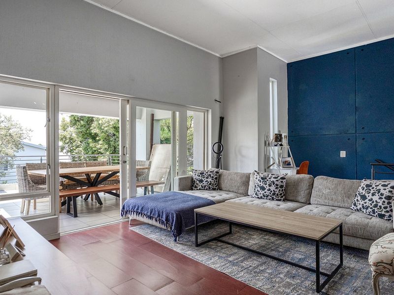Spacious living room featuring laminate flooring, a bold blue accent wall, and large sliding glass doors providing seamless access to the outdoor balcony area.