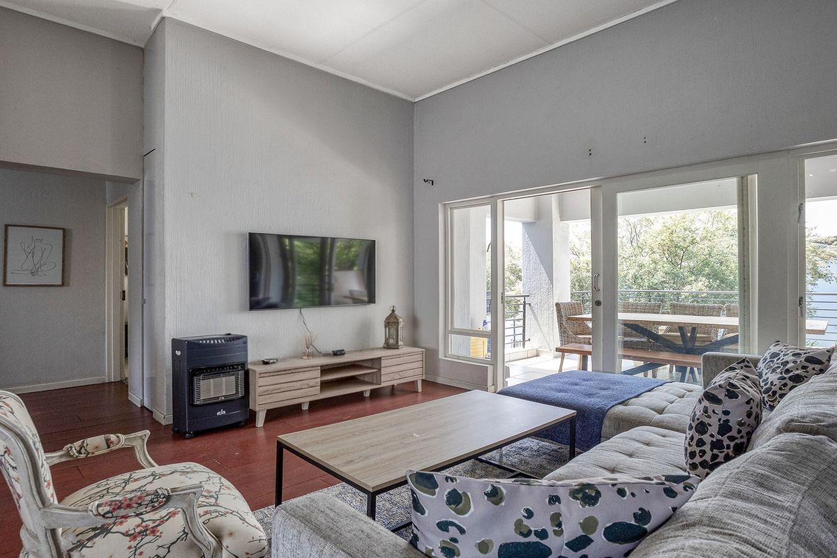 Spacious living room featuring high ceilings, laminate flooring, and large sliding glass doors that provide seamless access to the outdoor balcony area.