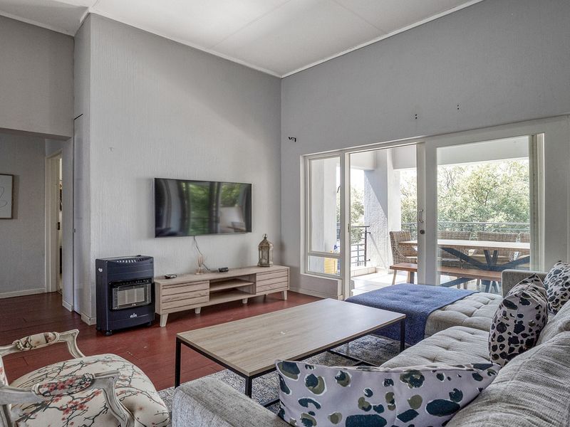 Spacious living room featuring high ceilings, laminate flooring, and large sliding glass doors that provide seamless access to the outdoor balcony area.