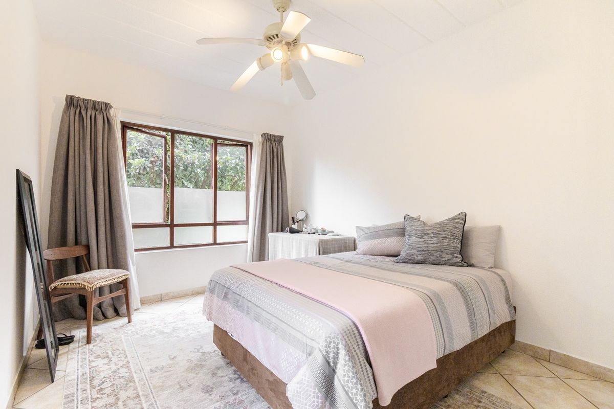 A well-lit bedroom featuring tiled flooring, a ceiling fan, and a window with natural light.