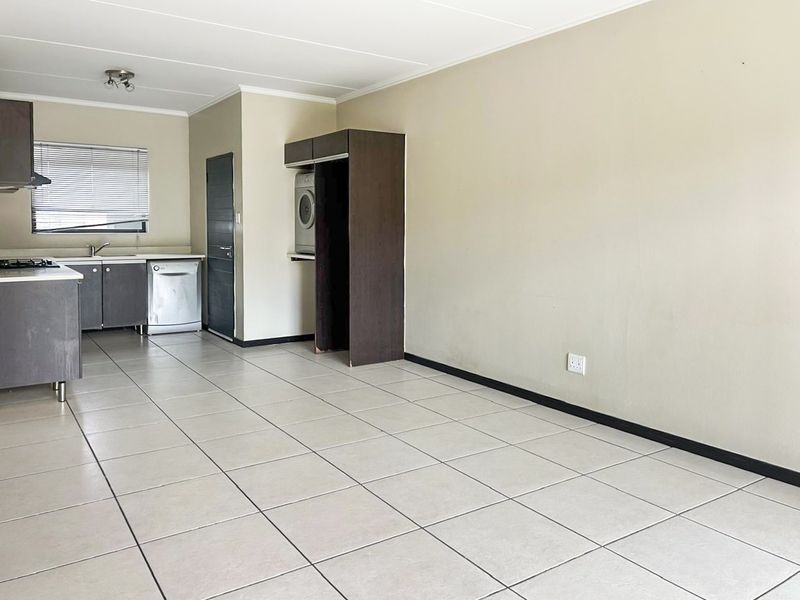 Open-plan living and kitchen area featuring tiled flooring, built-in cabinetry, gas hob, and a dedicated laundry cupboard space.
