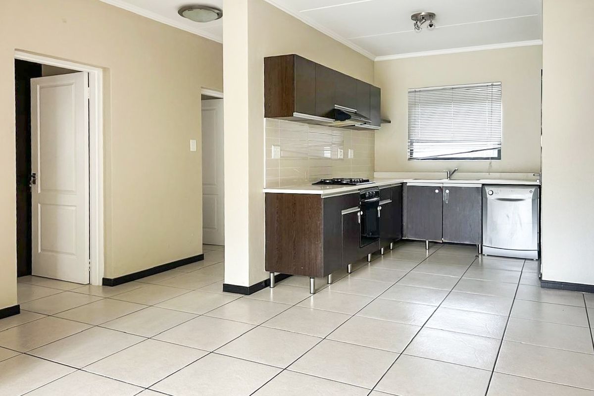 A functional kitchen featuring dark wood cabinetry, tiled flooring, built-in oven, gas hob, and a stainless steel sink with a tiled backsplash.