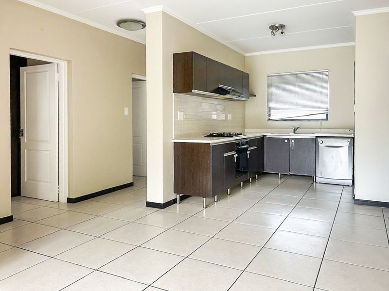 A functional kitchen featuring dark wood cabinetry, tiled flooring, built-in oven, gas hob, and a stainless steel sink with a tiled backsplash.