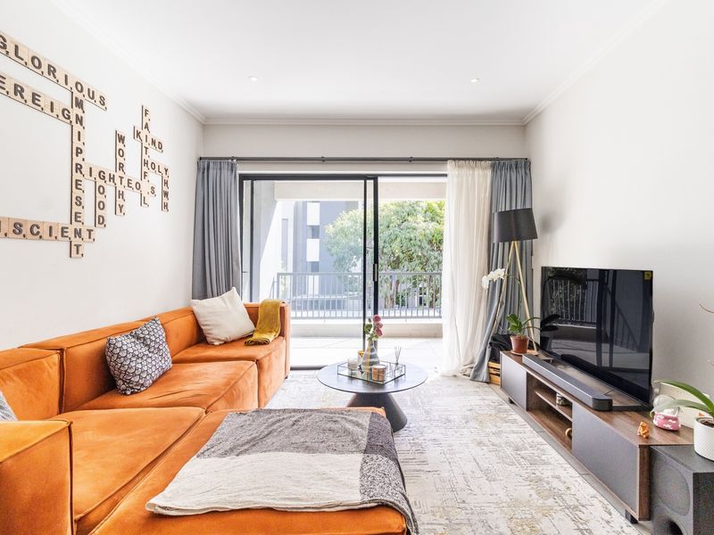 A bright and well-maintained living room featuring large sliding glass doors that open onto a private balcony, providing ample natural light.