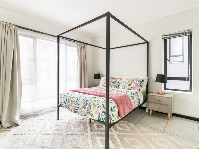 A bright and well-maintained bedroom featuring large windows, tiled flooring, and recessed ceiling lighting, offering a clean and comfortable living space.