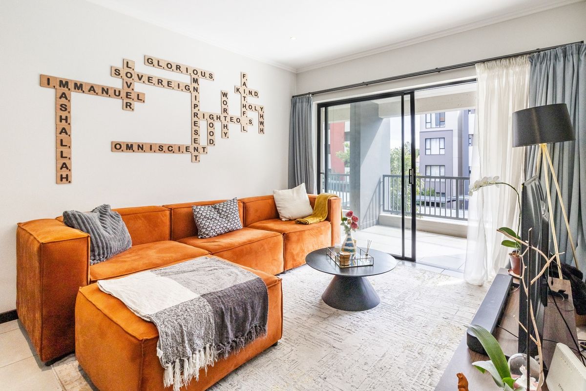 A bright and modern living room featuring tiled flooring, recessed lighting, and large sliding glass doors that open onto a private balcony.