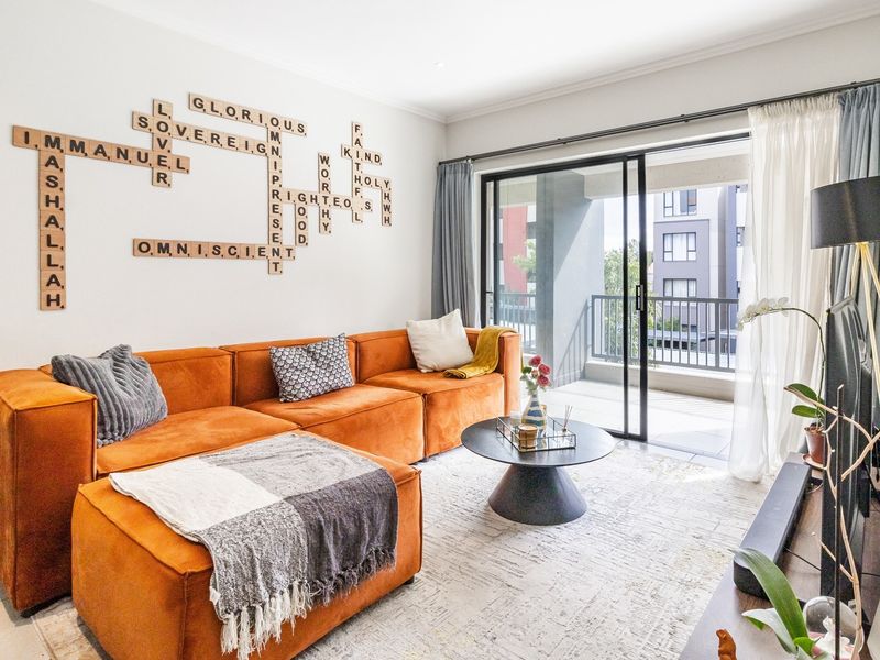 A bright and modern living room featuring tiled flooring, recessed lighting, and large sliding glass doors that open onto a private balcony.