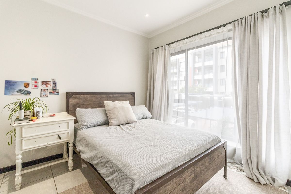 A bright bedroom featuring tiled flooring, cove cornicing, and a large sliding glass door that provides natural light and access to the exterior.