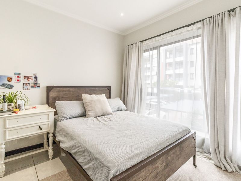A bright bedroom featuring tiled flooring, cove cornicing, and a large sliding glass door that provides natural light and access to the exterior.