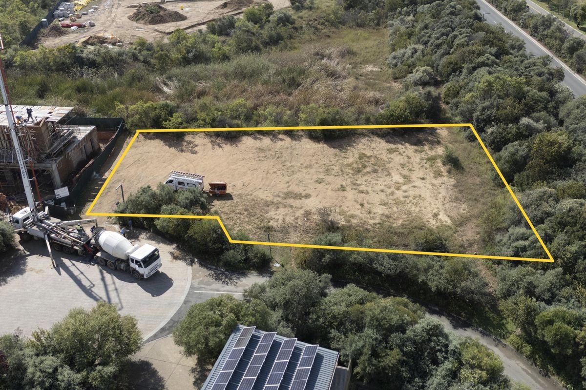 Aerial view of a vacant residential plot with clear boundary markings, situated in a developed area with surrounding vegetation.