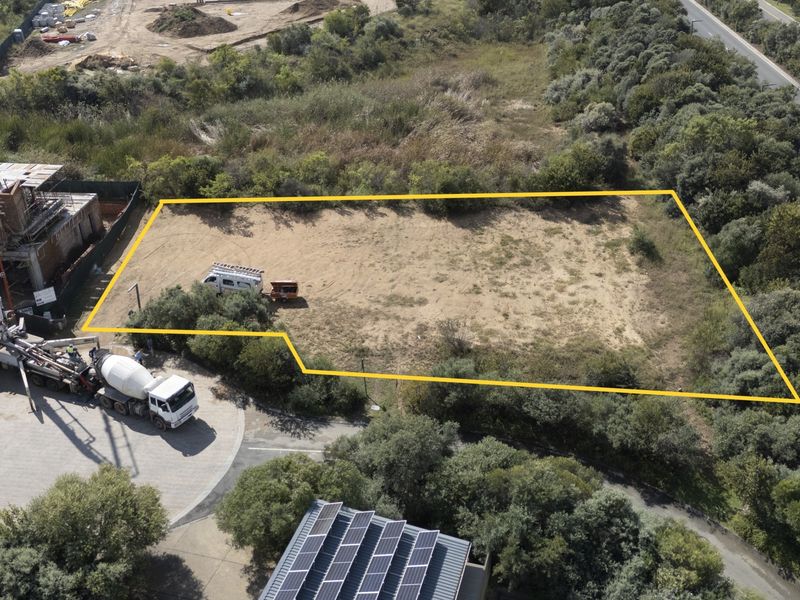 Aerial view of a vacant residential plot with clear boundary markings, situated in a developed area with surrounding vegetation.