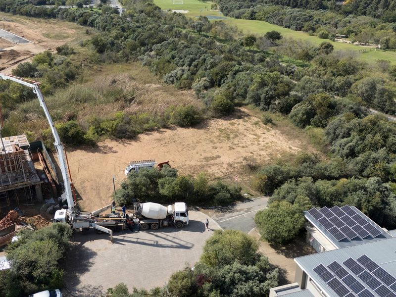 Aerial view of a residential construction site featuring active concrete pouring equipment and surrounding natural landscape.
