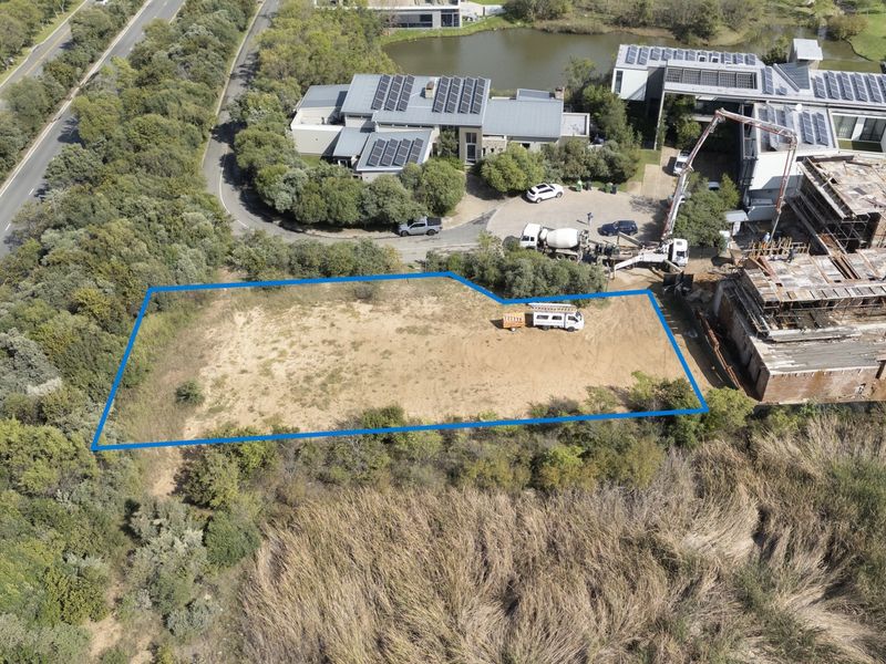An aerial view of a vacant residential plot of land with boundary lines highlighted, situated in a developed estate setting.