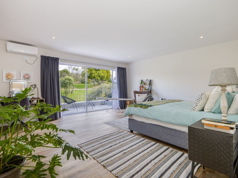 Spacious bedroom featuring laminate flooring, recessed lighting, an air conditioning unit, and large sliding glass doors opening to a private balcony.
