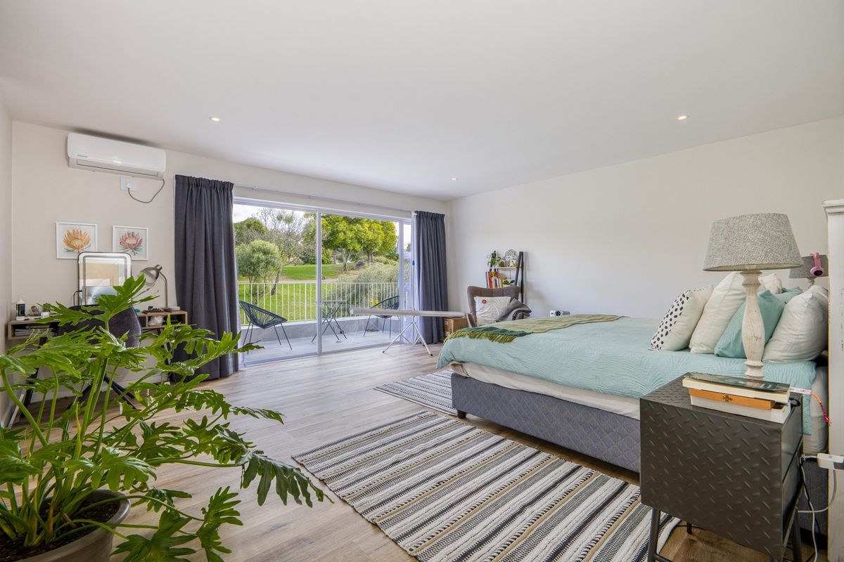 Spacious bedroom featuring laminate flooring, recessed lighting, an air conditioning unit, and large sliding glass doors opening to a private balcony.
