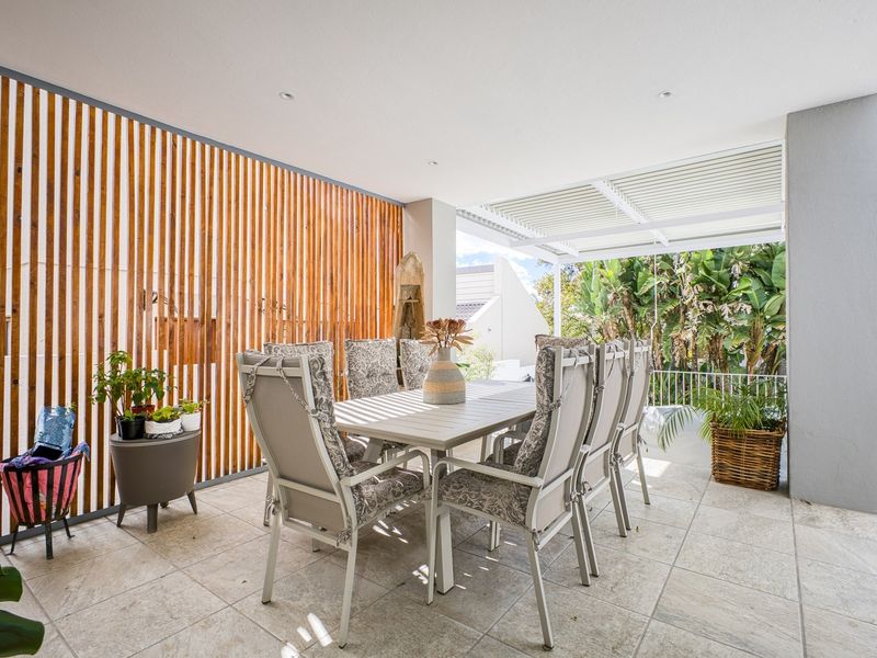 A well-maintained covered patio featuring tiled flooring, a timber slat privacy screen, and a modern louvred roof system for adjustable outdoor living.