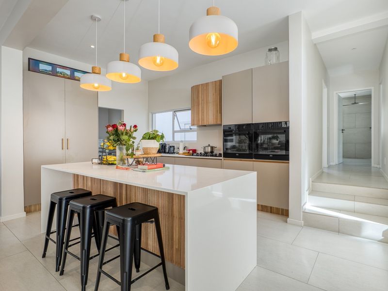 Modern kitchen featuring a central island with quartz countertops, sleek built-in cabinetry, integrated double ovens, and stylish pendant lighting.