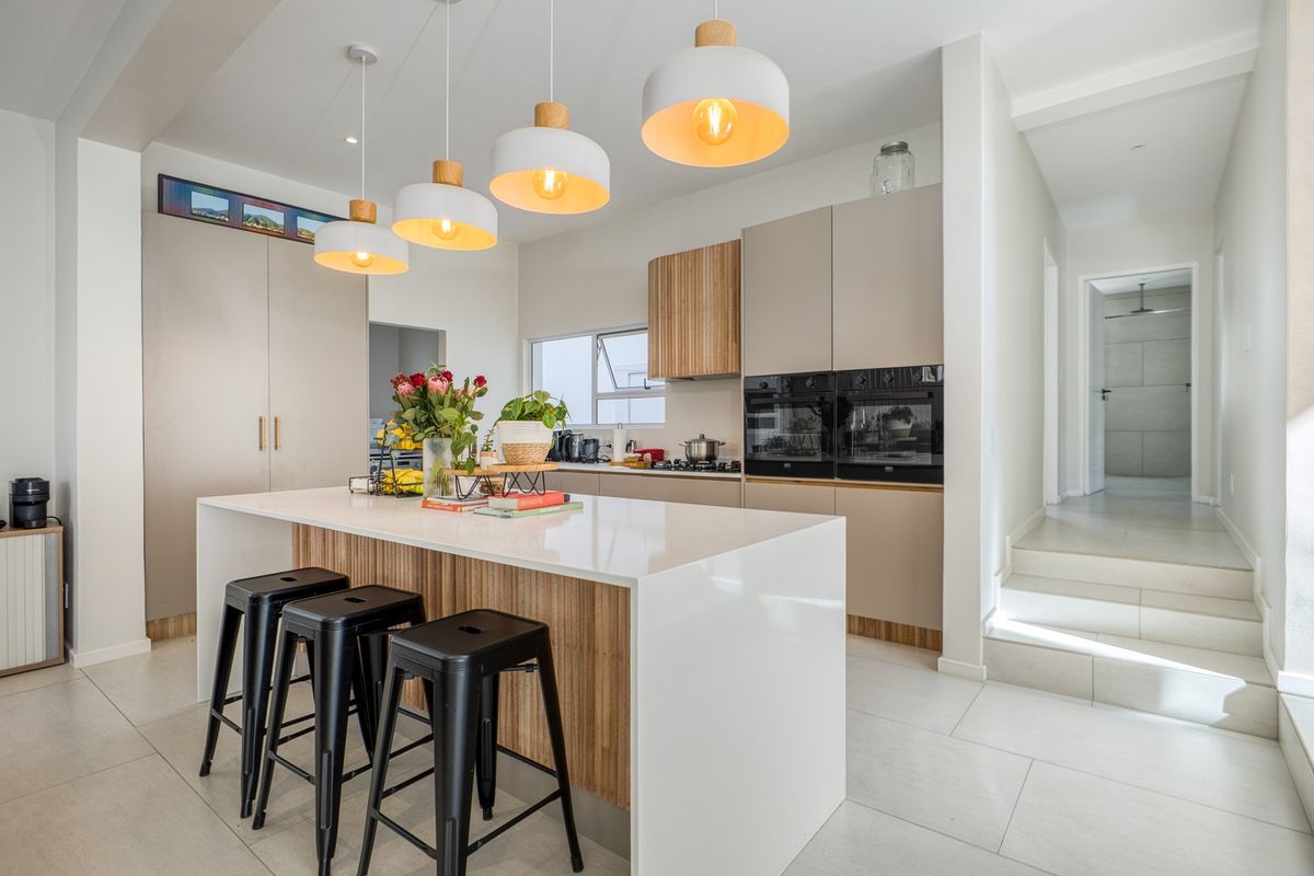 Modern kitchen featuring a central island with quartz countertops, sleek built-in cabinetry, integrated double ovens, and stylish pendant lighting.