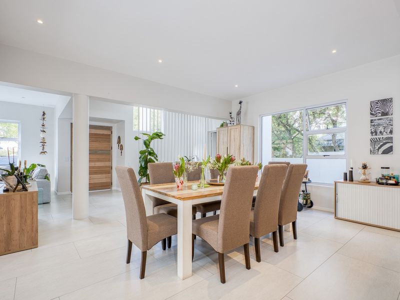 Bright and spacious dining area featuring neutral tiled flooring, recessed lighting, and large windows that provide ample natural light.