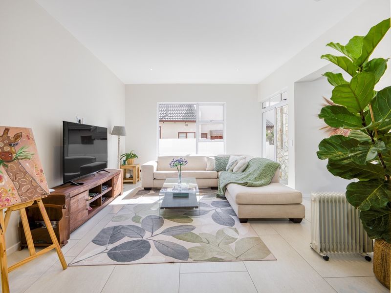 A bright and spacious living room featuring neutral tiled flooring, recessed lighting, and large windows that provide ample natural light.