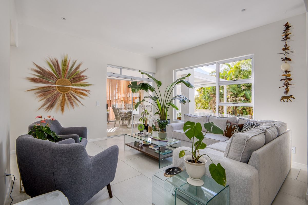 A bright and modern living room featuring large windows, tiled flooring, and seamless access to an outdoor patio area.