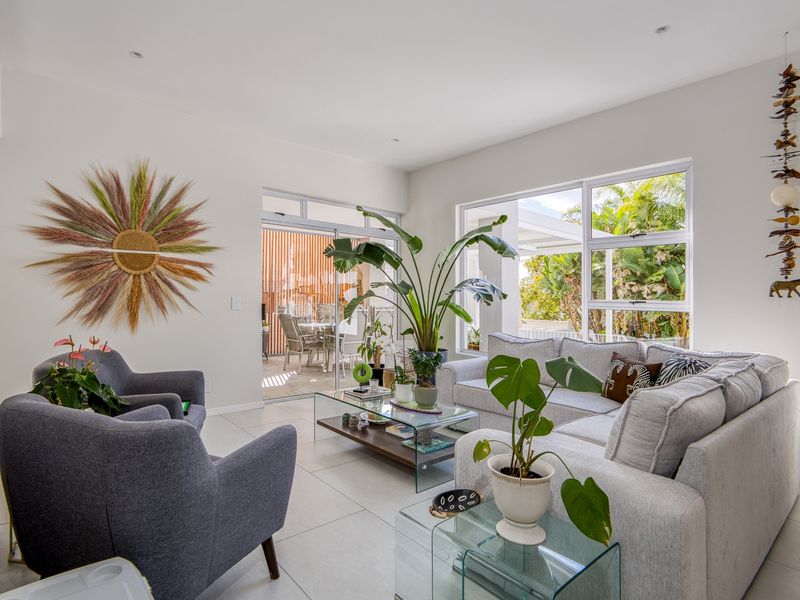 A bright and modern living room featuring large windows, tiled flooring, and seamless access to an outdoor patio area.