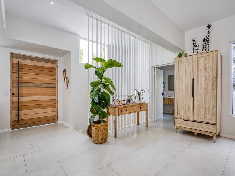 Bright and modern entrance hall featuring large format floor tiles, a striking timber front door, and a contemporary vertical slat room divider.