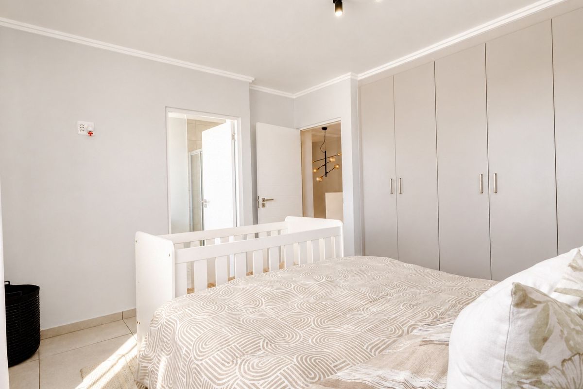 A well-maintained bedroom featuring neutral tiled flooring, ample built-in cupboard storage, and direct access to an en-suite bathroom.