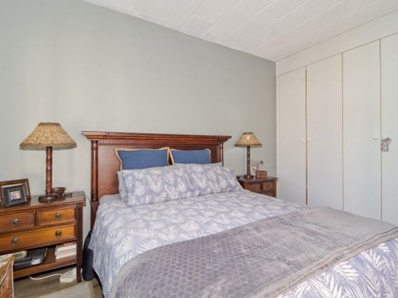 A comfortable bedroom featuring built-in cupboards and neutral wall finishes, providing a functional and well-maintained sleeping space.