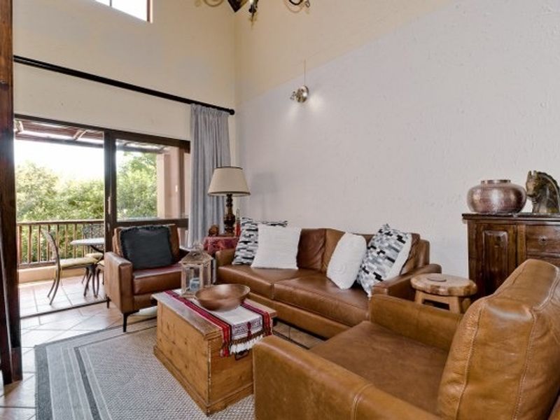 Spacious living room with high ceilings, tiled flooring, and direct access to a private balcony through large sliding glass doors.