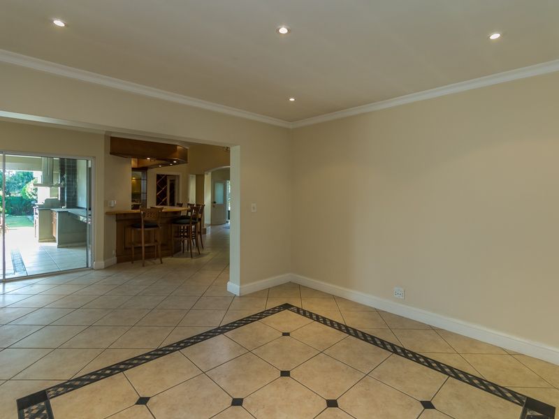 Spacious open-plan living area featuring tiled floors with decorative inlay, recessed lighting, and seamless access to an outdoor patio and built-in bar area.